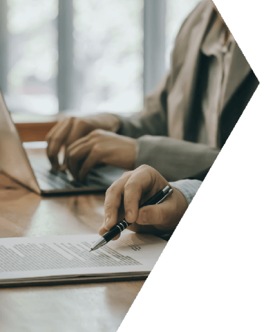A lawyer signing a document while working at a laptop